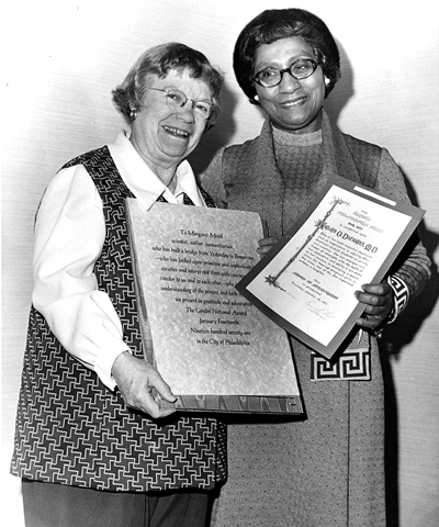 Dr. Margaret Mead and Dr. Helen O. Dickens stand side by side holding award plaques in a photo from 1971.